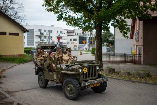 Uczestnicy podczas inscenizacji i wydarzenia. Jadą autem terenowym.